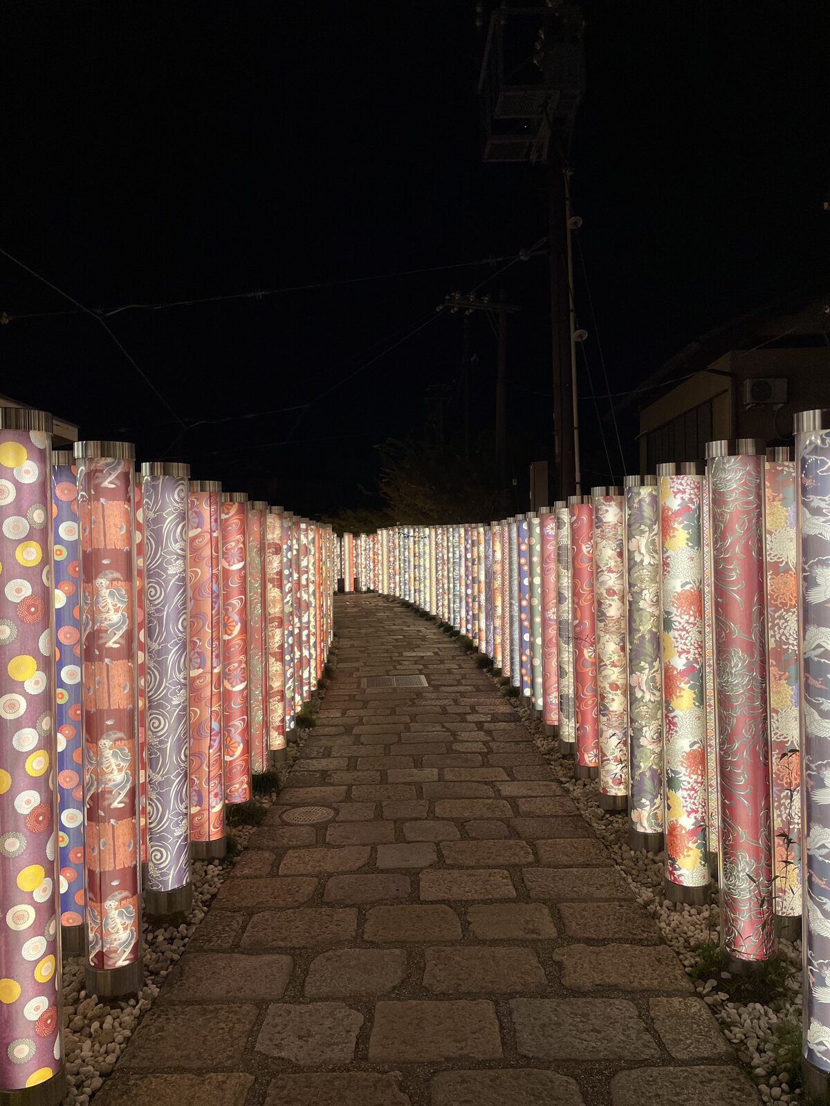 Illuminated pillars with kimono patterns at the Kimono Forest in Arashiyama at night