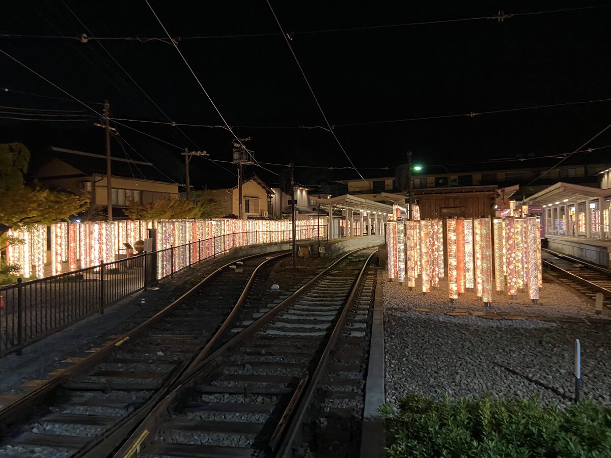 Kimono Forest pillars glowing next to the tram tracks at Randen Arashiyama Station