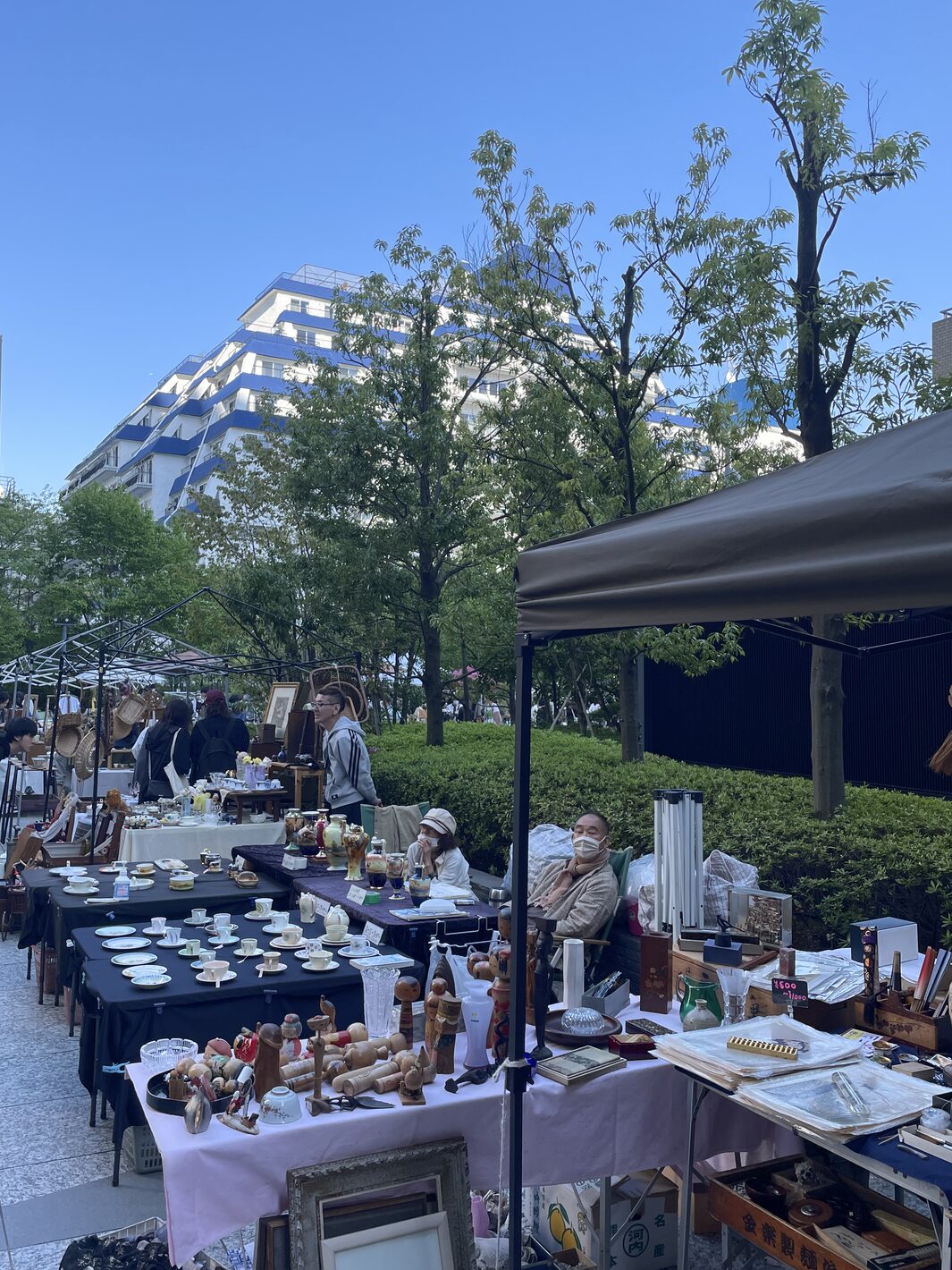 Rows of antique stalls with teacups, vases and kokeshi dolls on the plaza of Shibuya Garden Tower