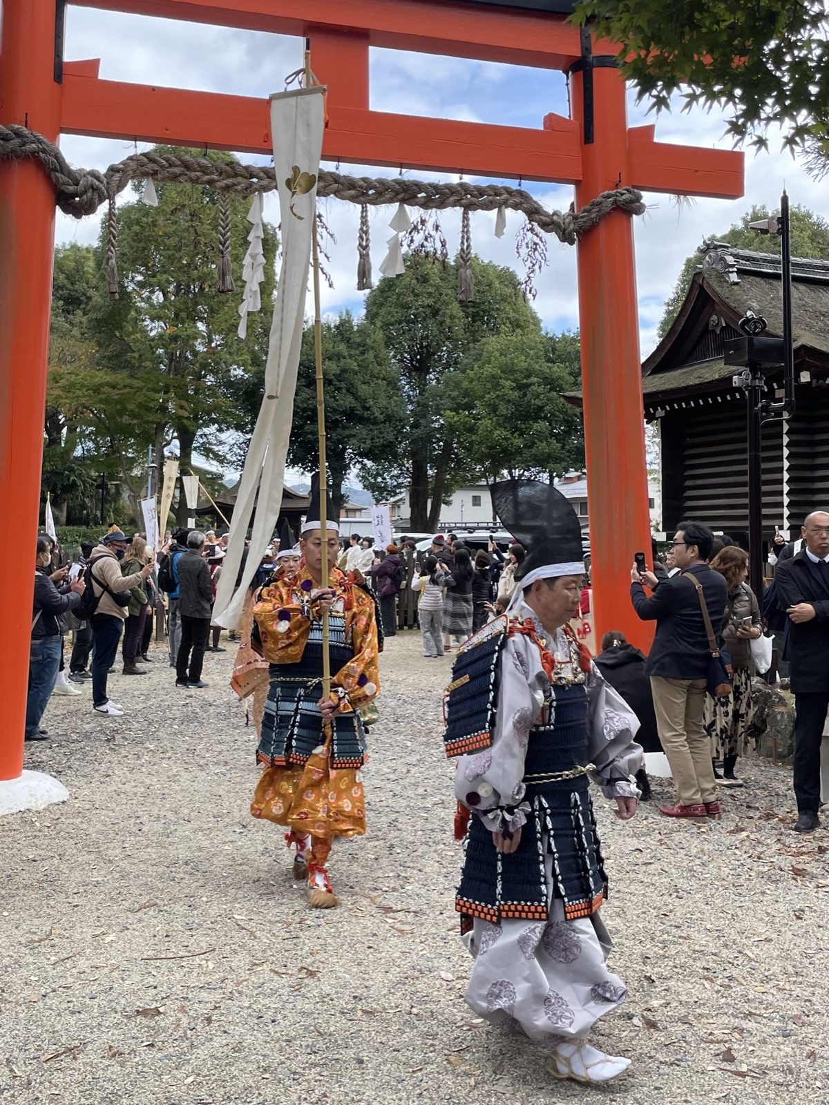 Participants in samurai armour walking through a red torii at Kamigamo Shrine during the Yoroi Kizome-shiki